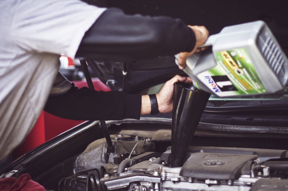 Mechanic pouring fresh oil into an engine through a funnel